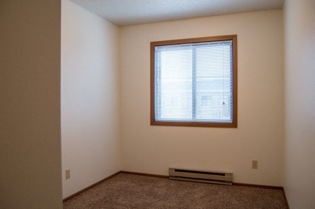 an empty room with a window and a carpet. Fargo, ND Candlelight Apartments